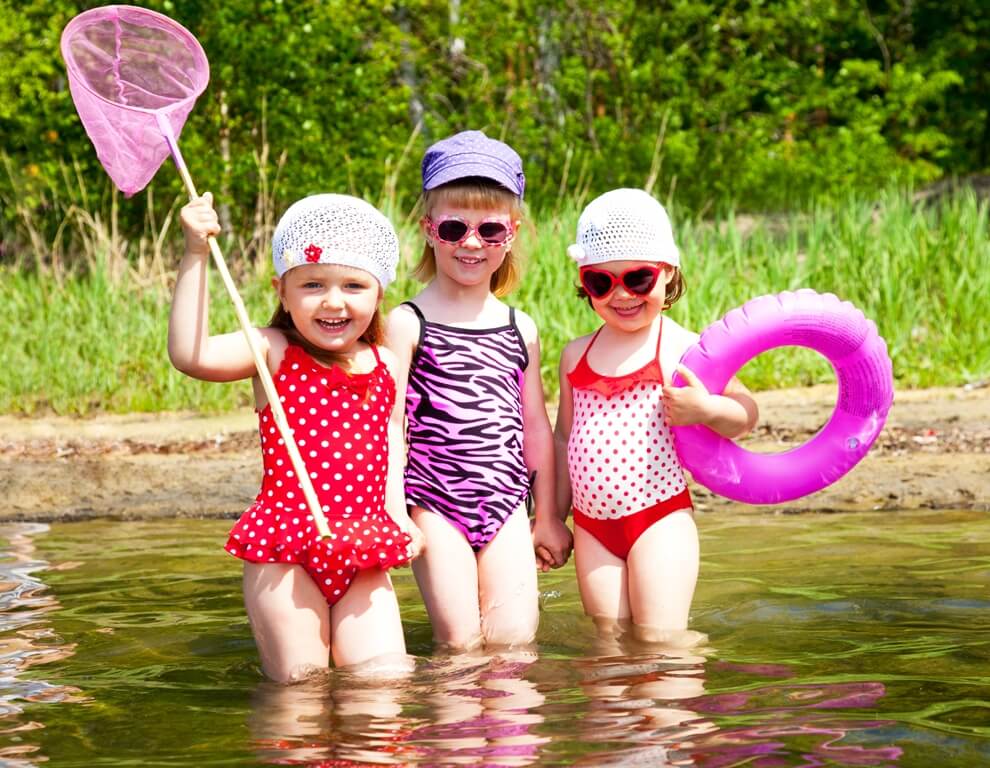 Photo of 3 little girls in swimming suits at lake Shutterstock.