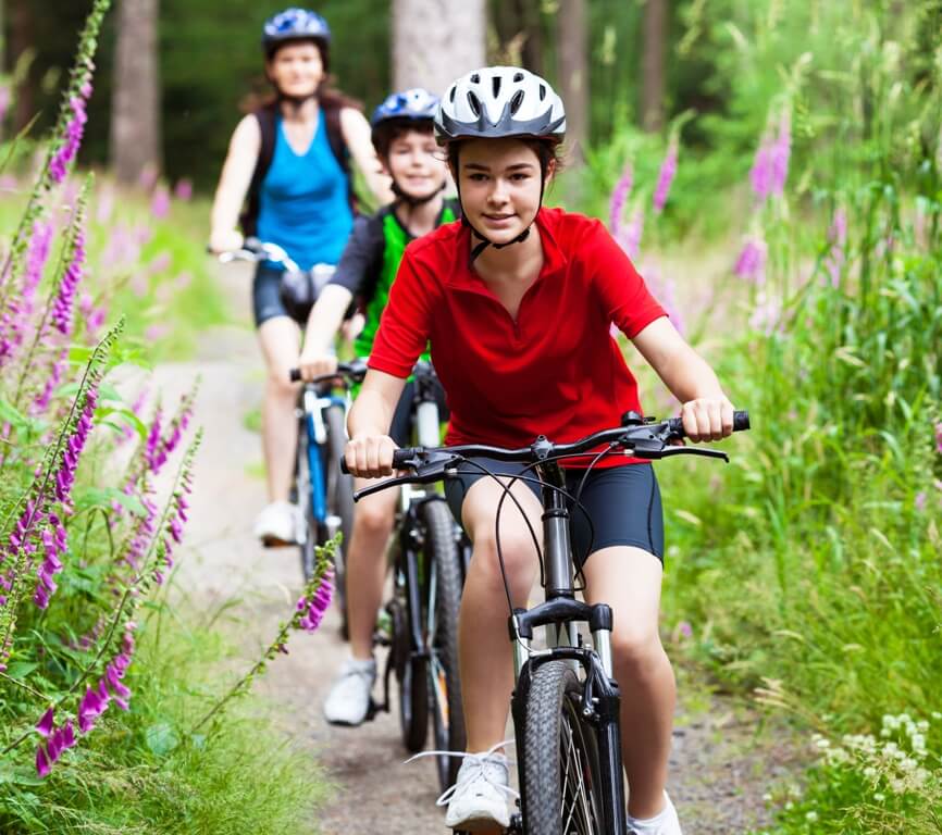 Image of young family biking along flowered biking trail.