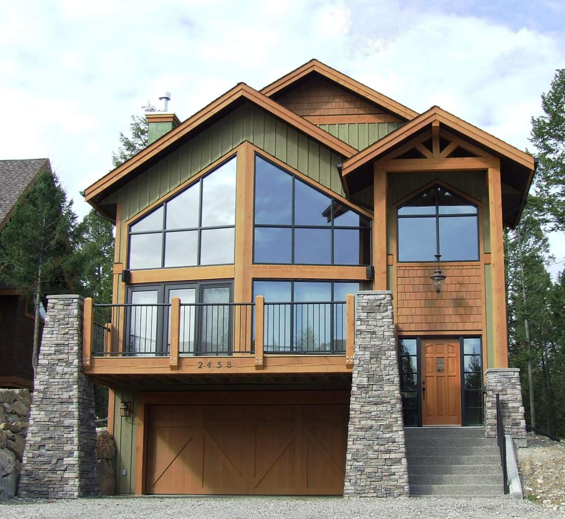 A tall alpine styled house with large window features and a single garage