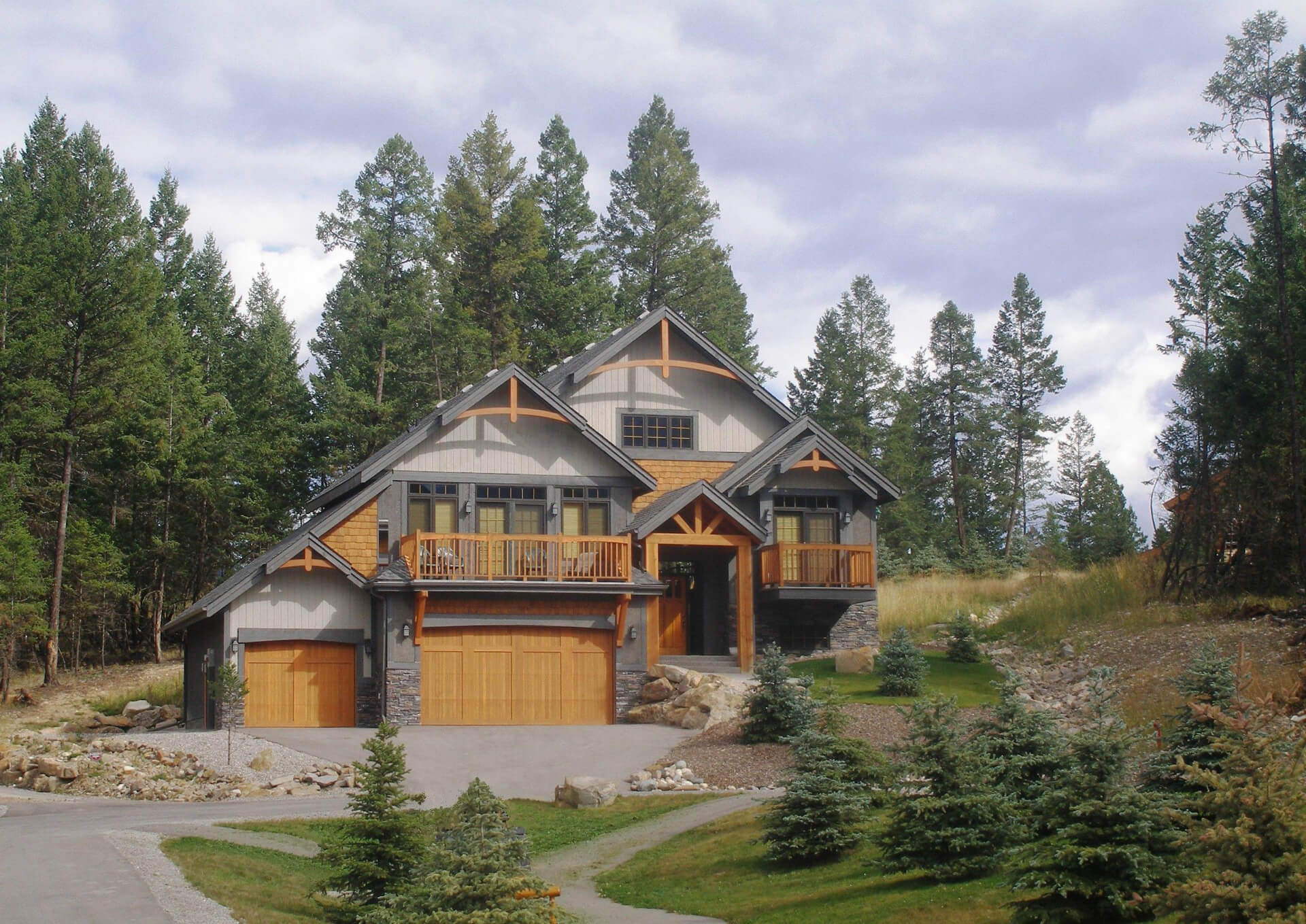 A tall alpine styled house with large window features and a single garage